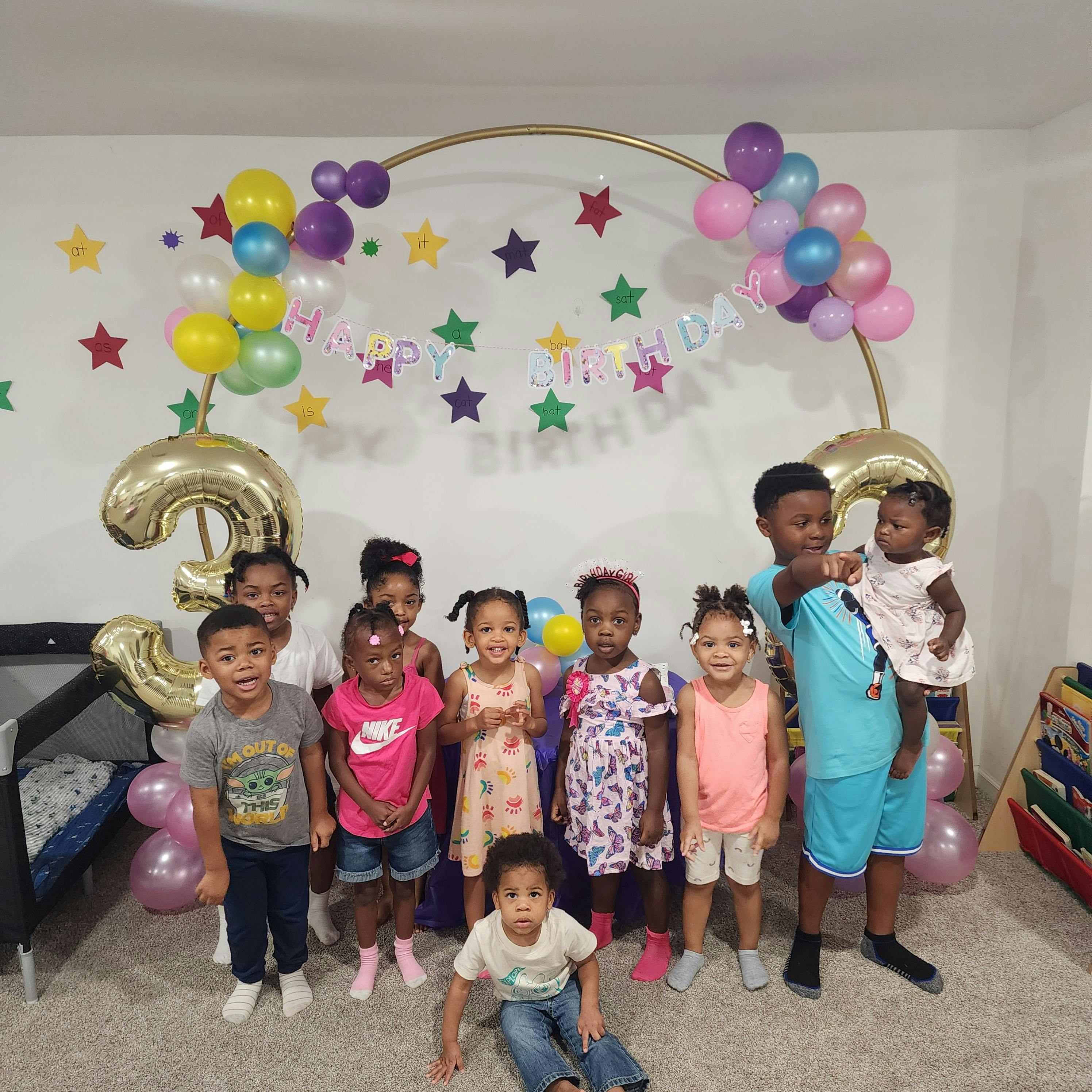 Group of children and teens posing in front of a balloon arch and stars