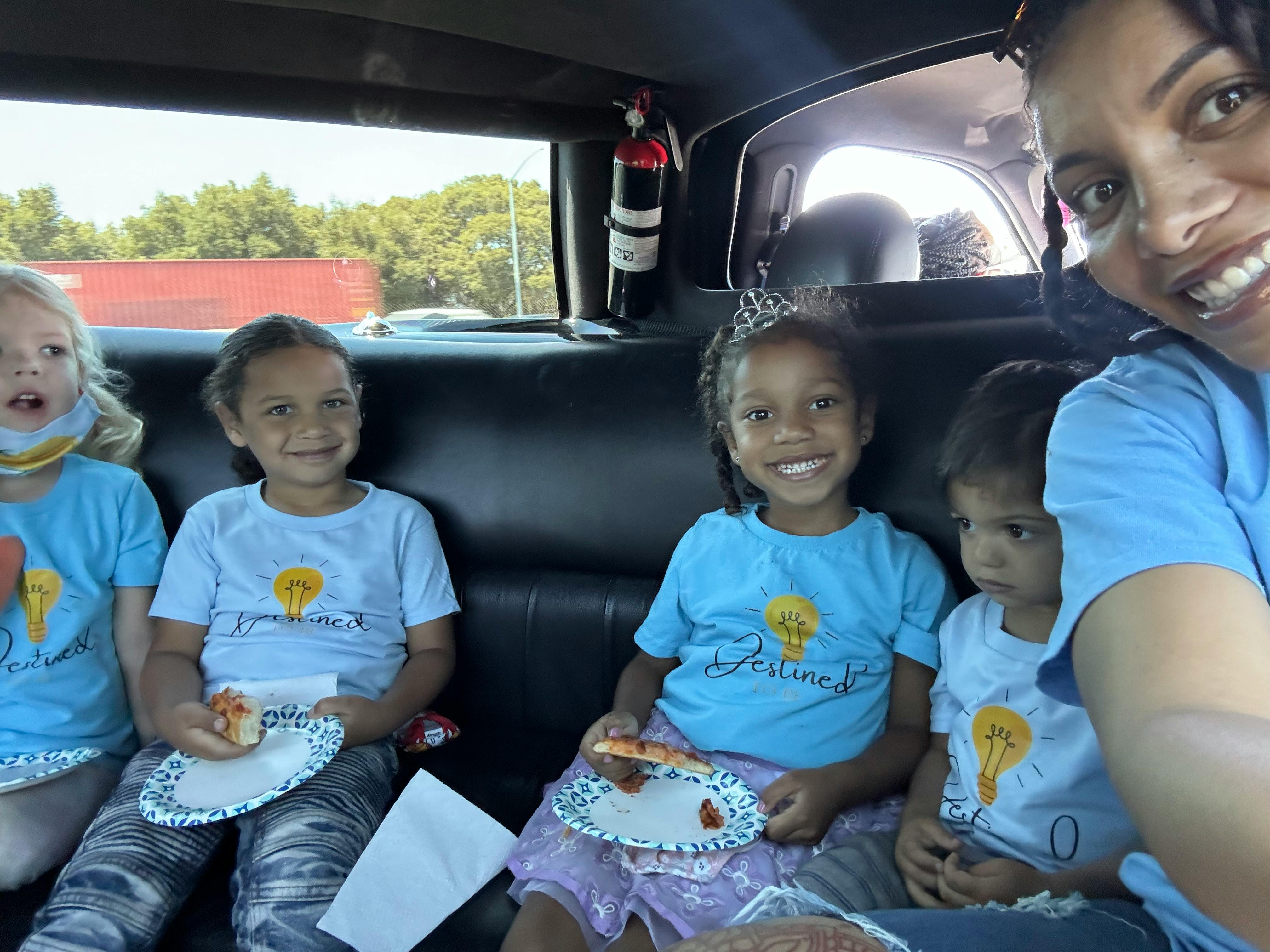 Person taking a selfie with four children in a vehicle