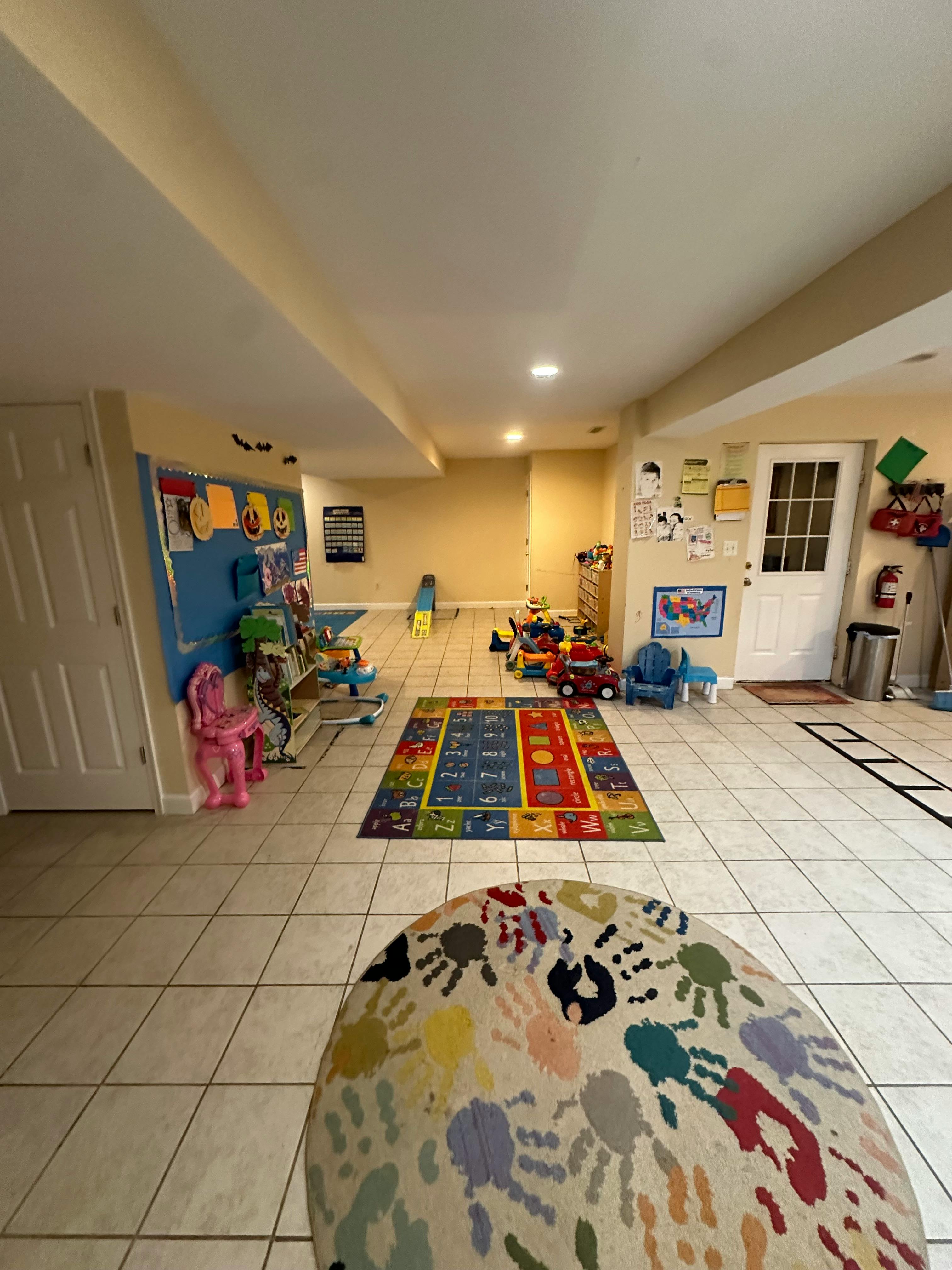 Playroom with toys, colorful rug, and a beanbag chair with handprints