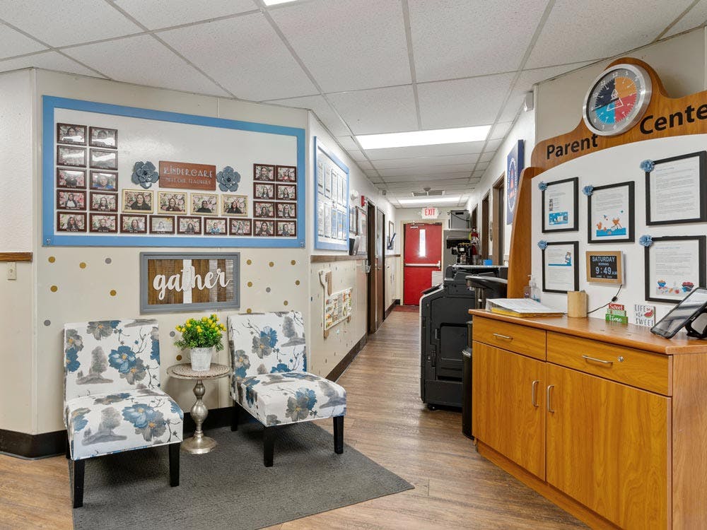 Hallway in a childcare center with seating, a teacher photo board, and parent center