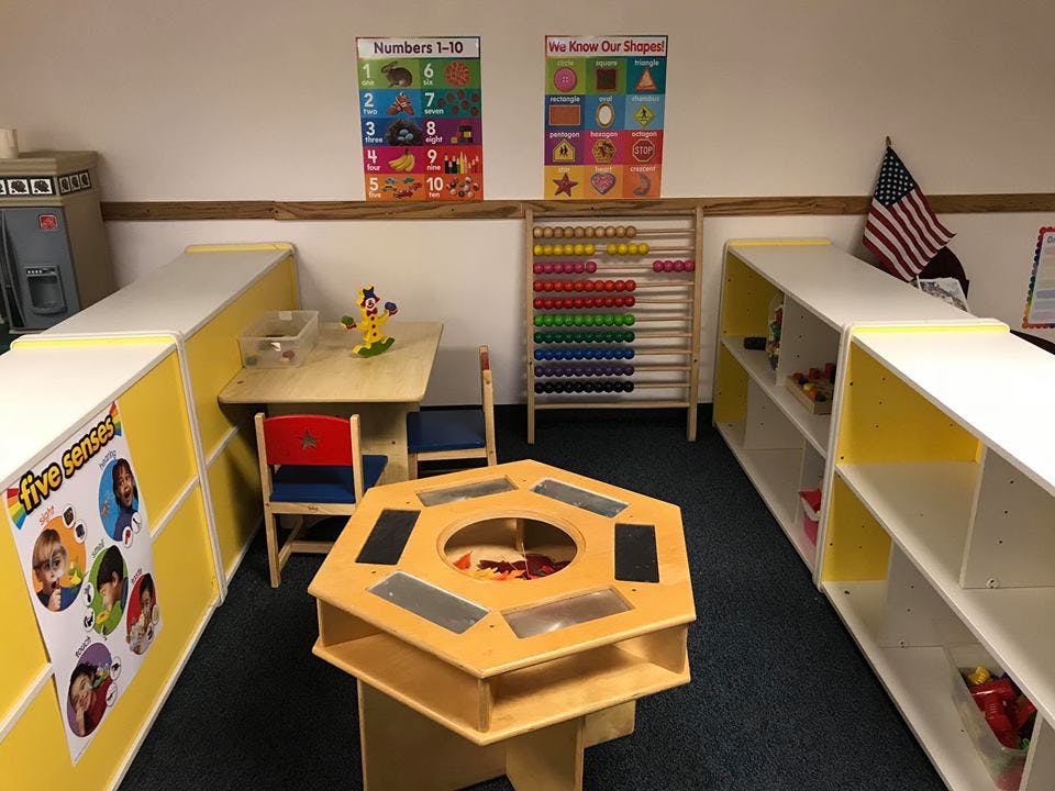 Classroom with small tables, chairs, shelves, and an abacus