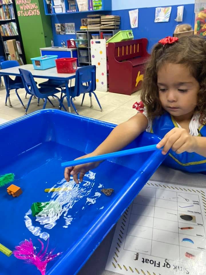 Child playing with water and toys in a blue bin