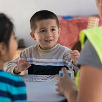 Child at a table looking at another person