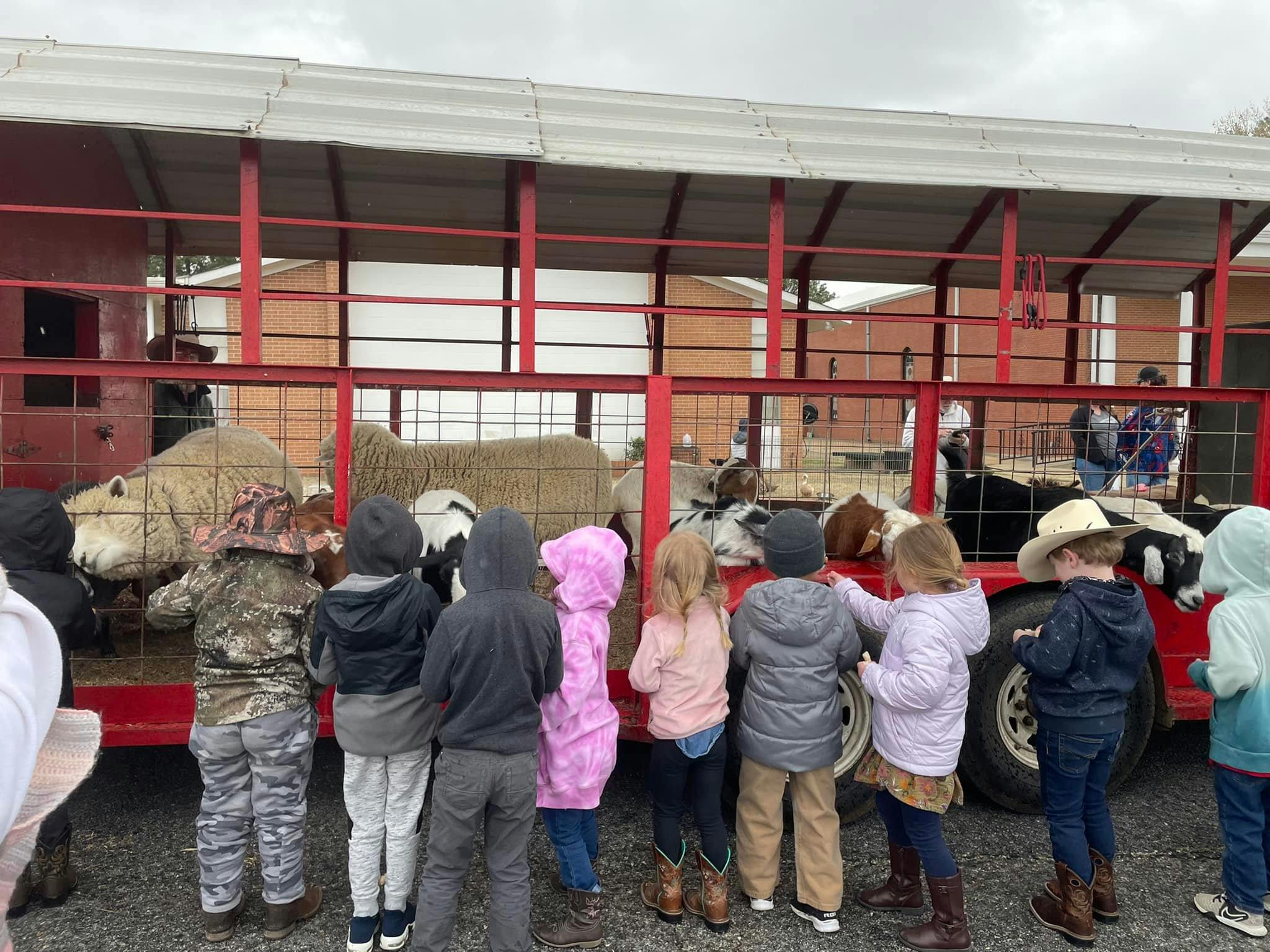 Children looking at animals in a red trailer