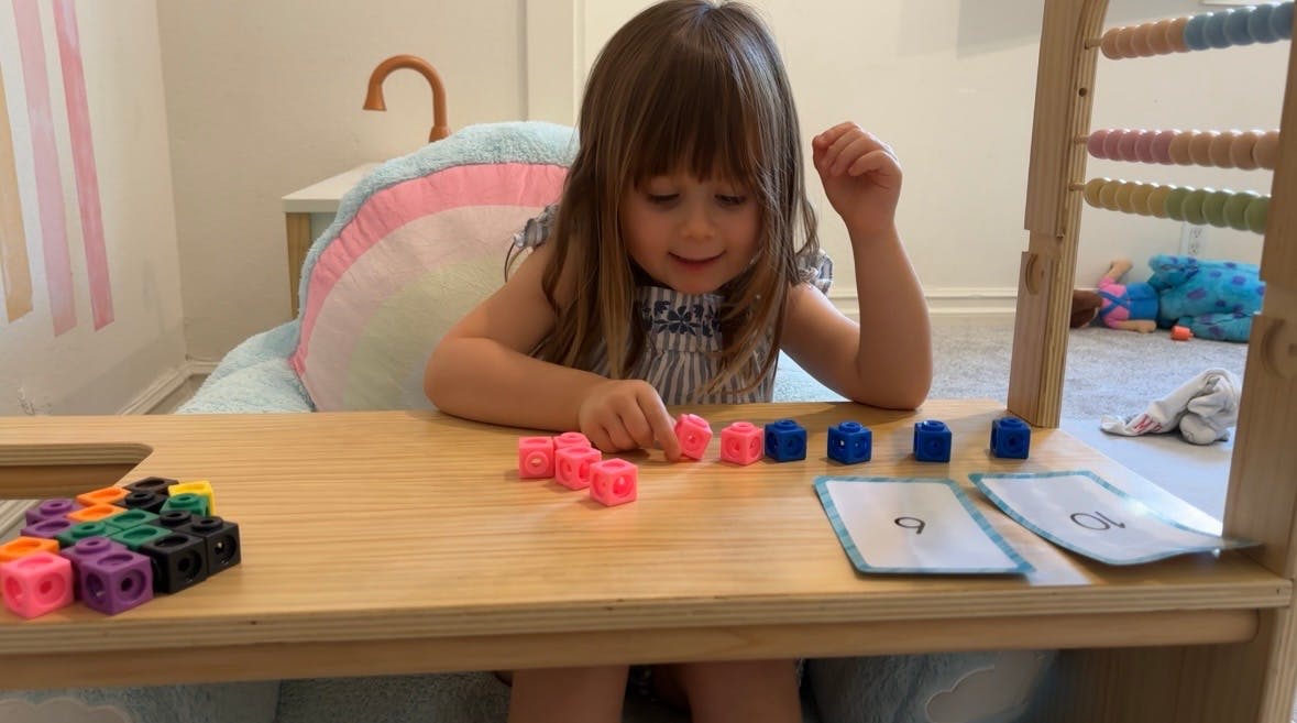 Child playing with counting blocks and number cards on a table