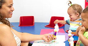 Adult and two children playing with bubble wands at a table
