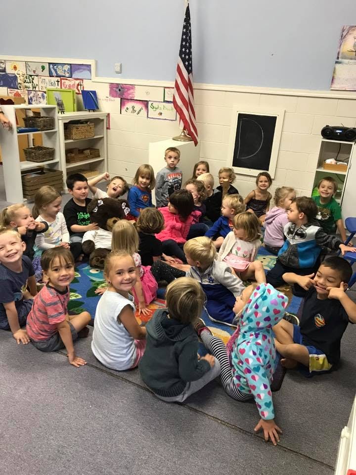 Group of children sitting on a rug in a classroom
