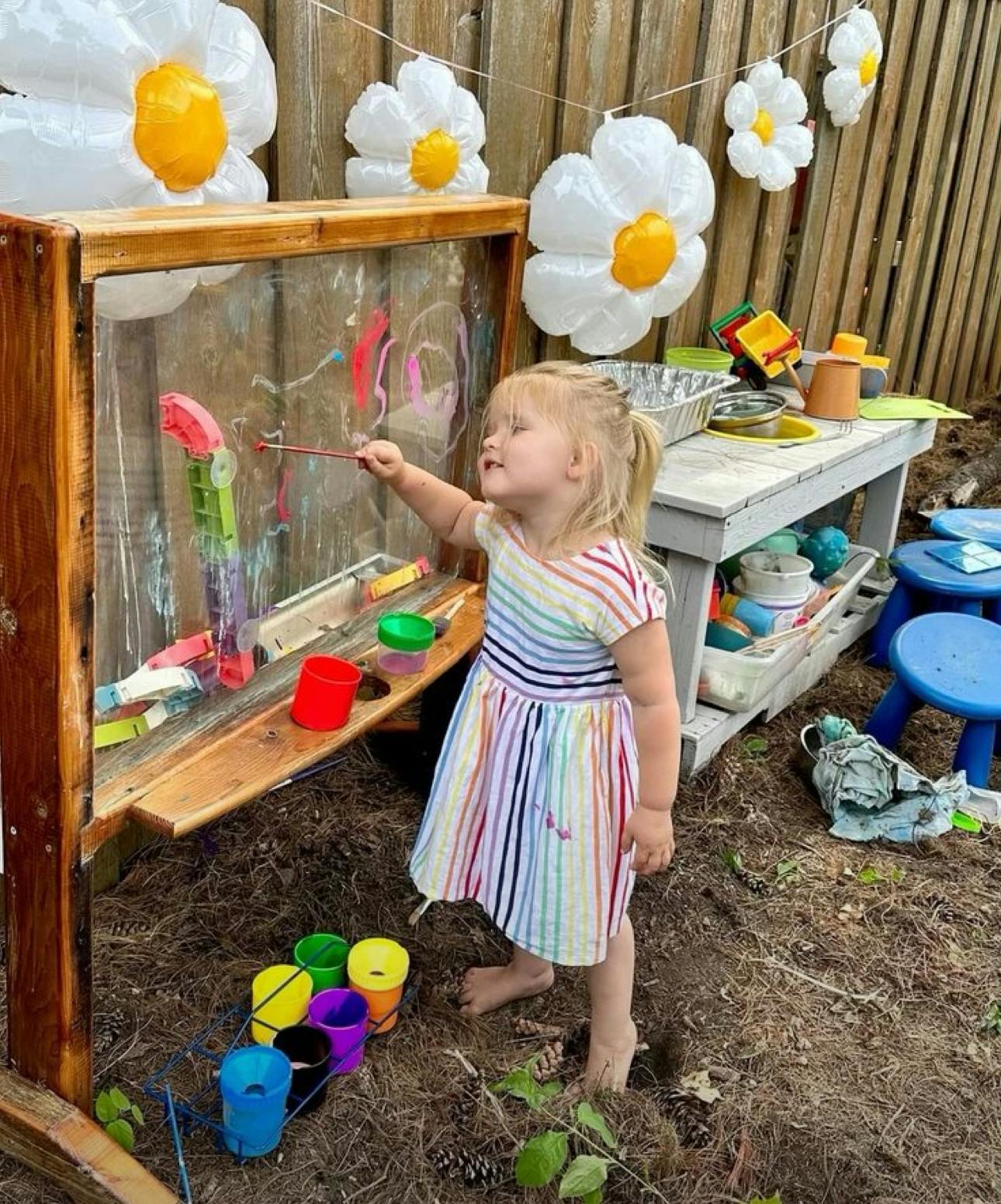 Child painting on an outdoor plexiglass art easel