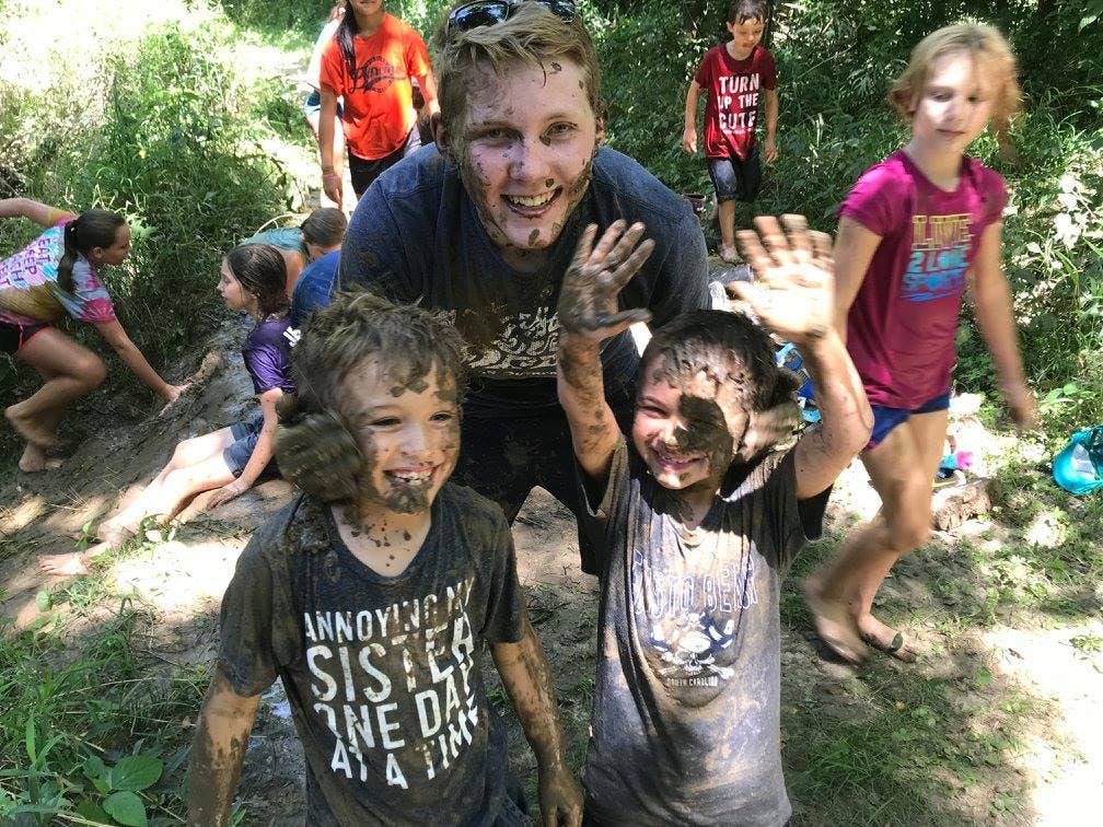 People covered in mud, smiling and waving