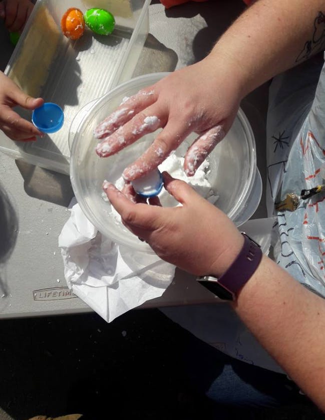 Person with flour-covered hands holding a small container over-turned cup