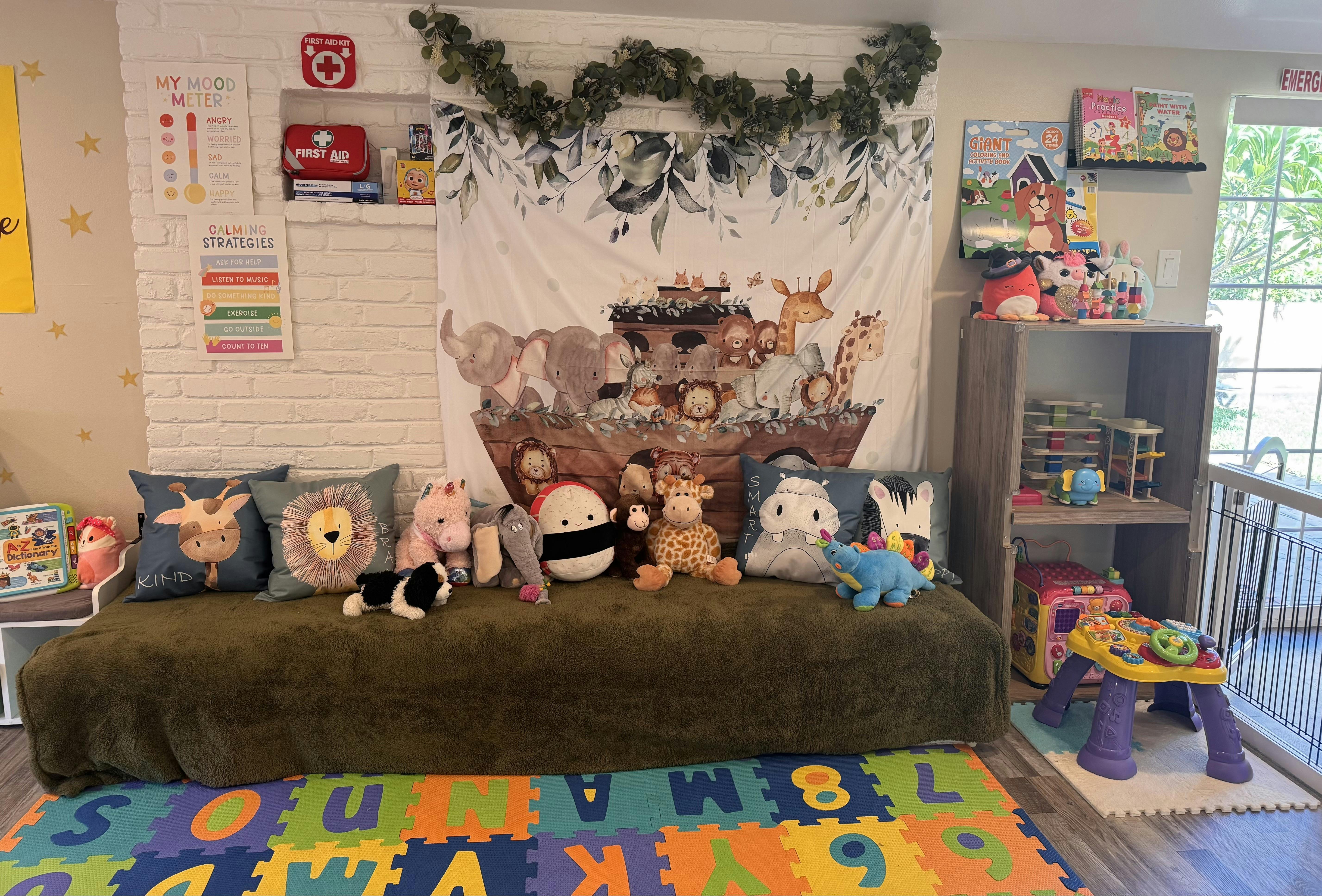 Children's play area with a couch, stuffed animals, and an alphabet mat