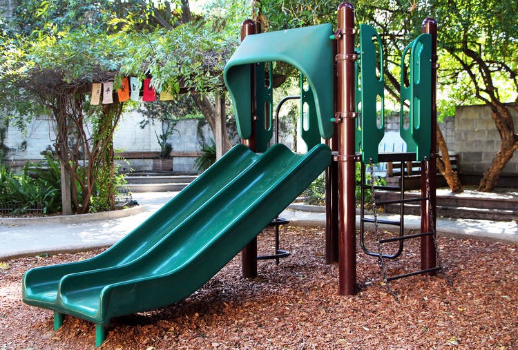 Green playground slide and climbing structure