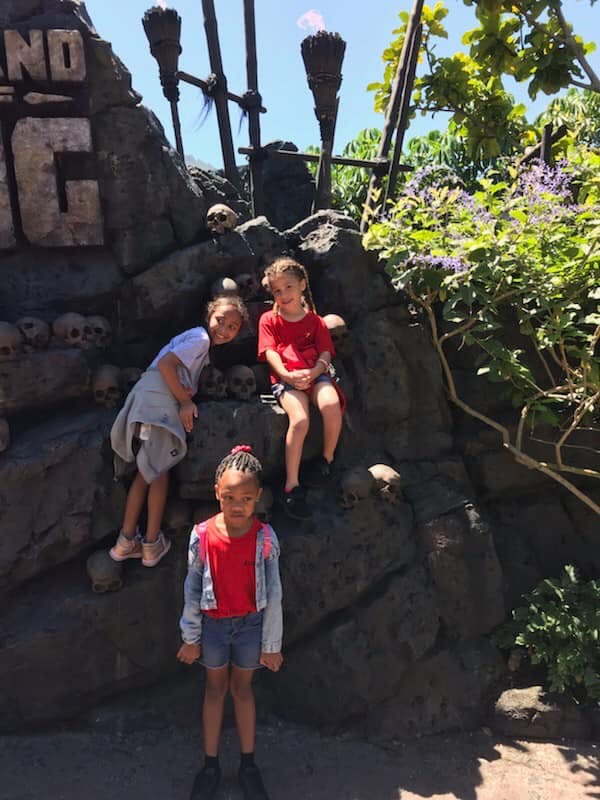 Three children posing on and in front of a rock formation