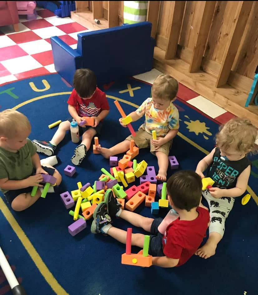 Children playing with colorful building blocks on a blue rug