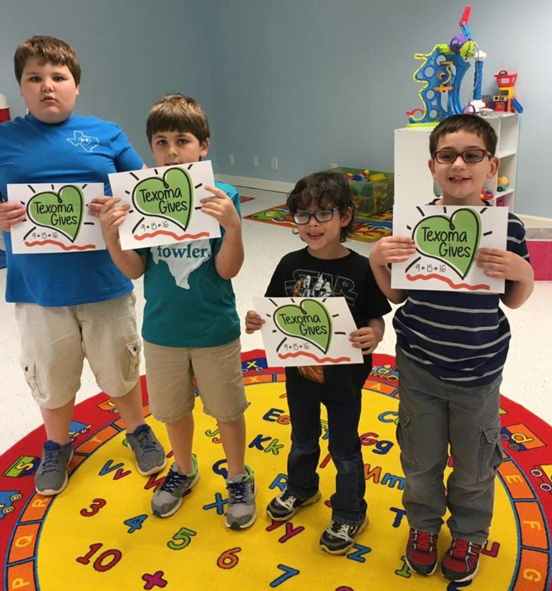 Four children holding signs that say "Texoma Gives"