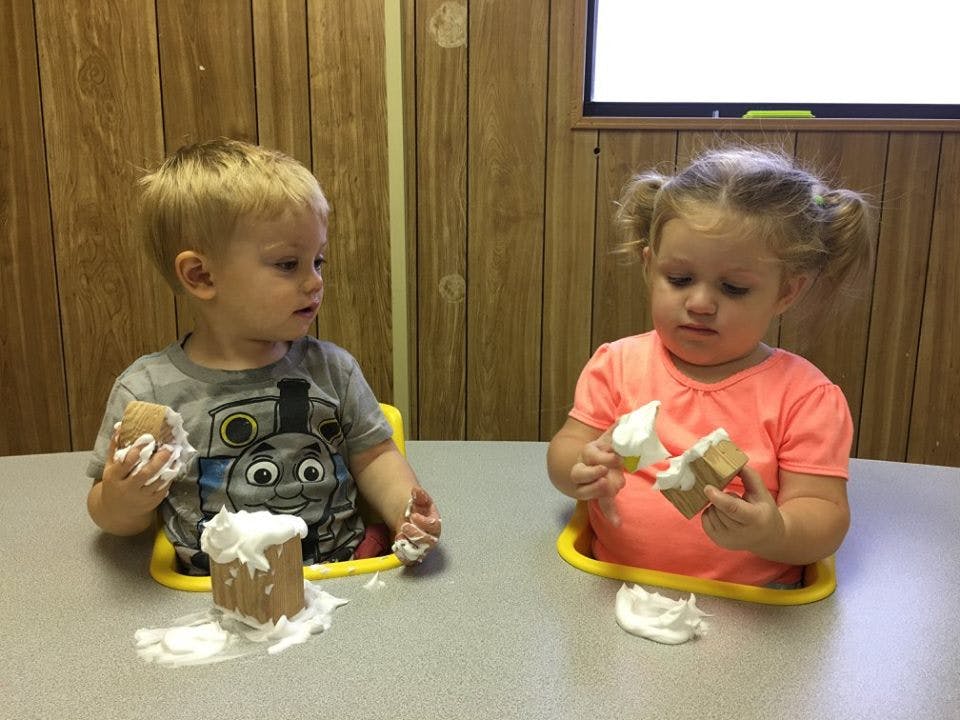 Two children playing with whipped cream at a table