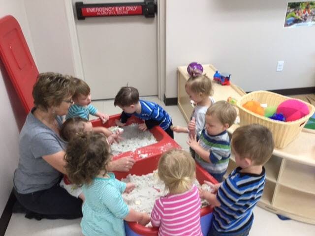 Adult and children playing in a sensory bin
