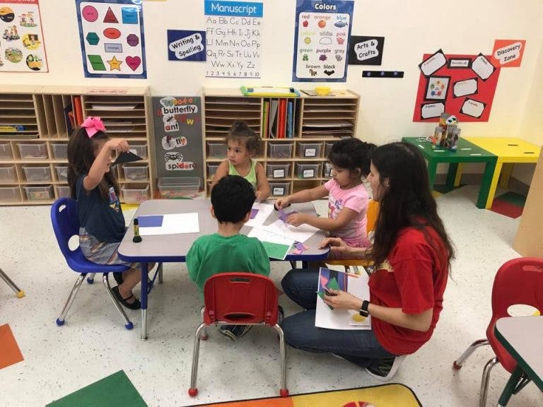 Adult and children sitting at a table in a classroom