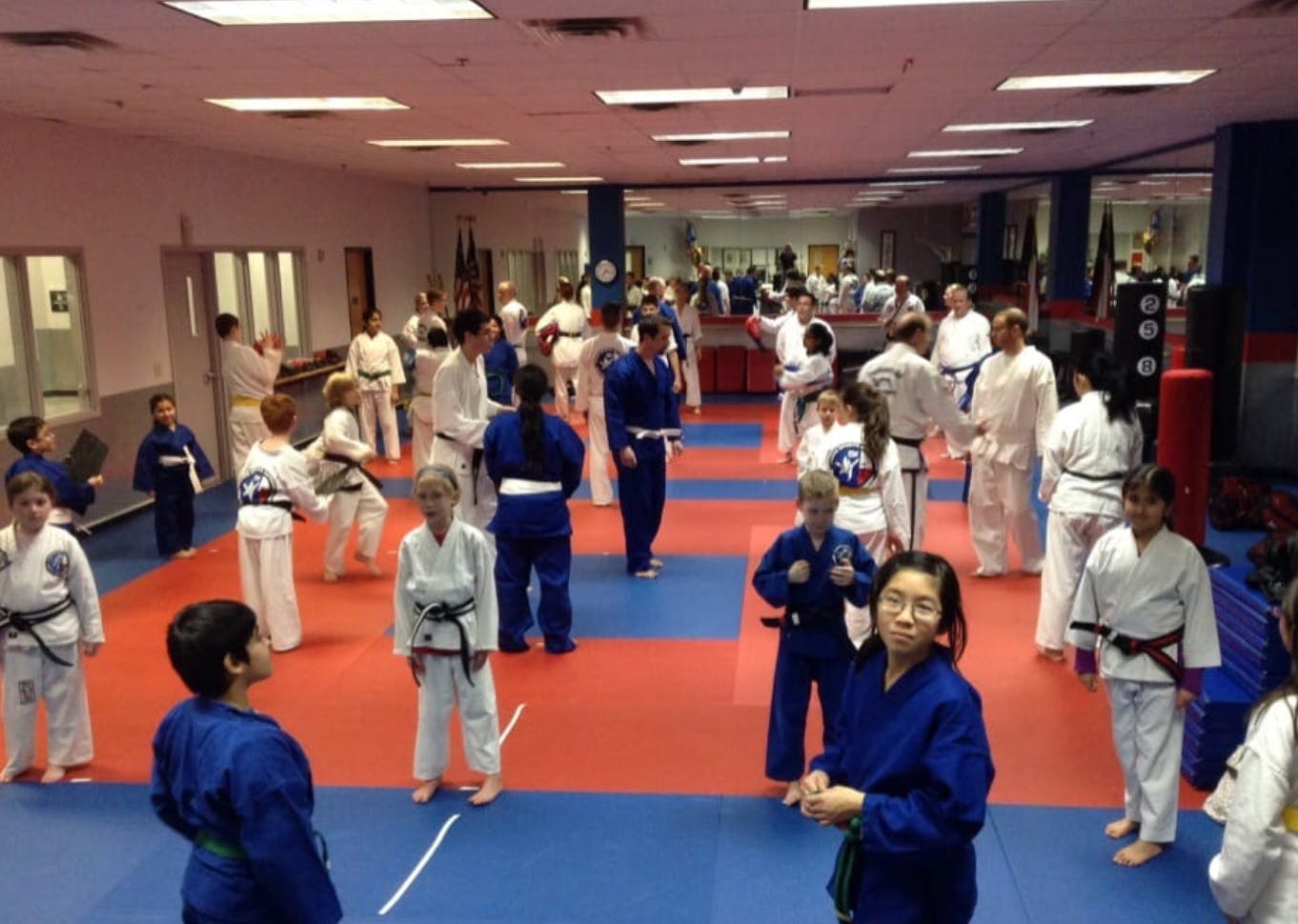 Many people and children in martial arts uniforms in a studio