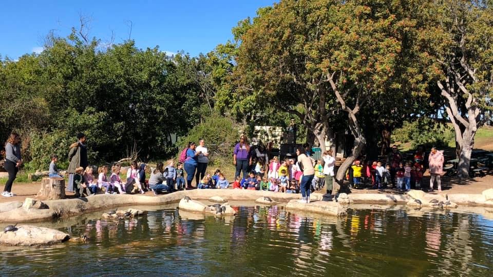 Group of people and children gathered by a pond