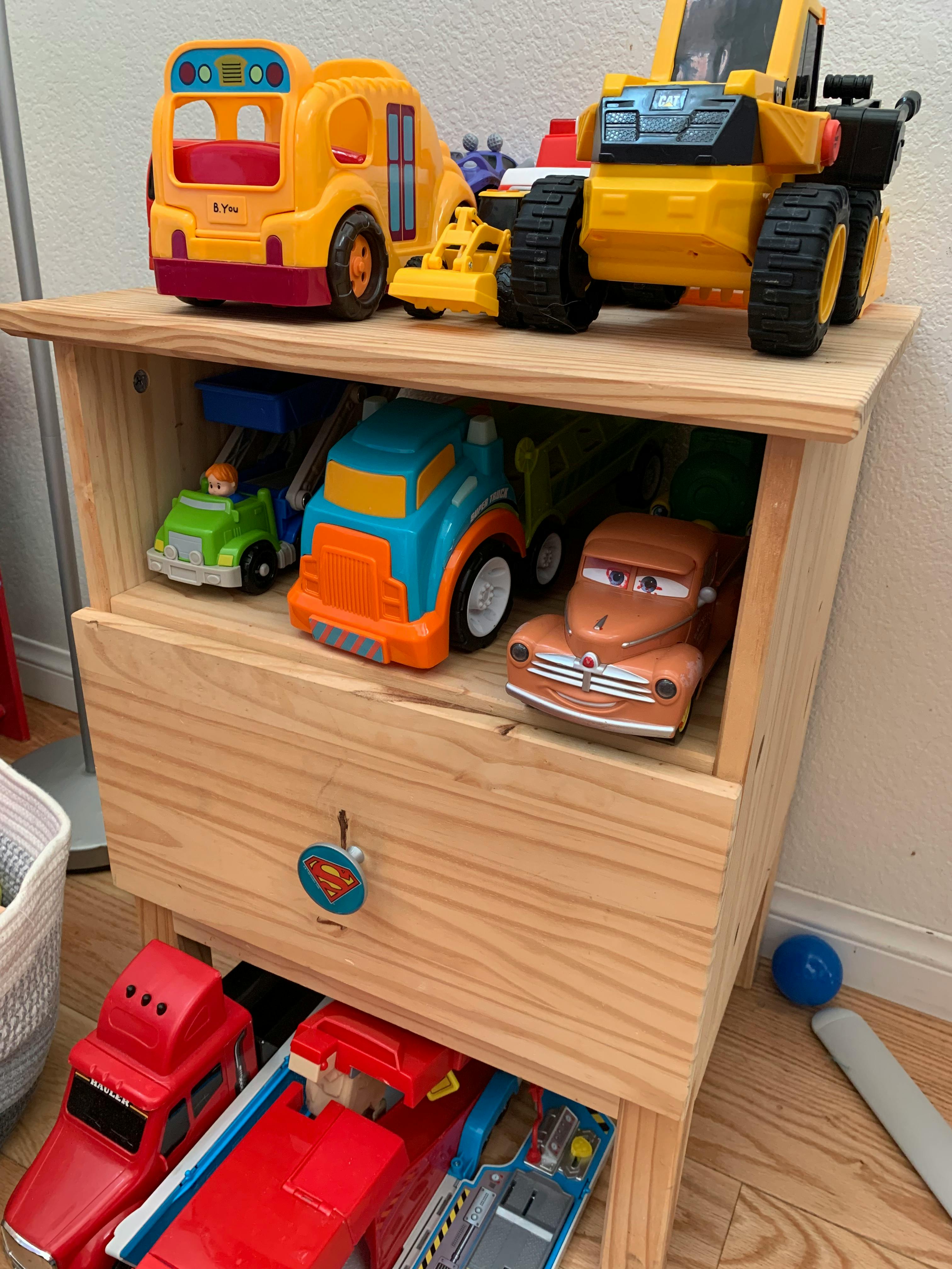 Toy vehicles on and in a wooden storage unit