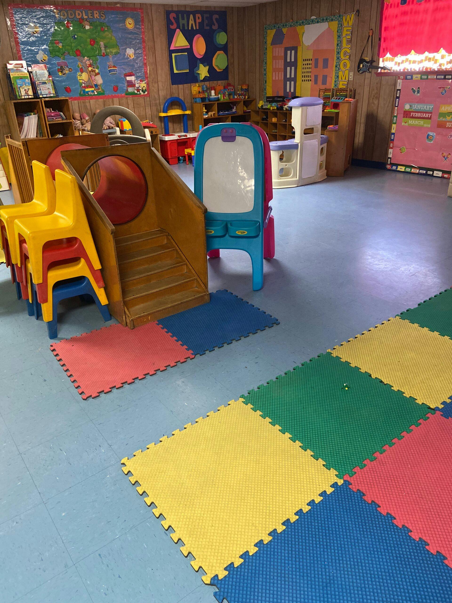 Playroom with a wooden slide, easel, and colorful floor mats