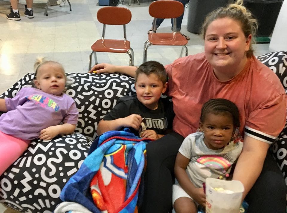 Adult and three children sitting on a patterned couch