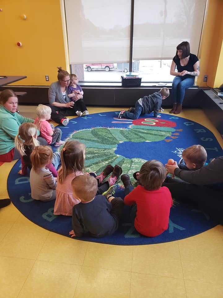 Adults and children sitting on a rug in a classroom