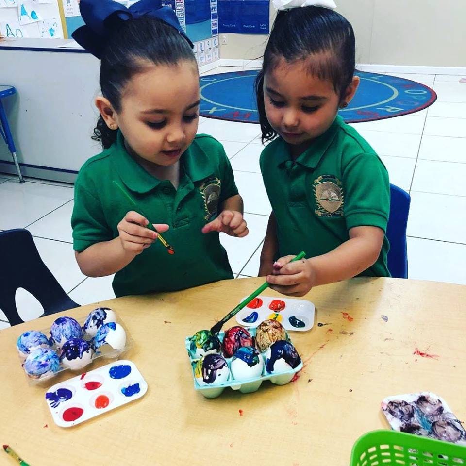 Two children painting eggs at a table
