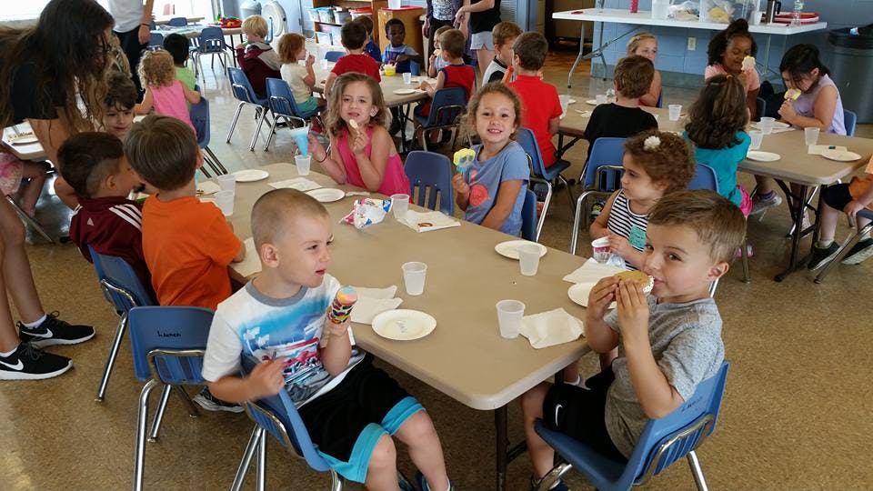 Children sitting at tables eating snacks