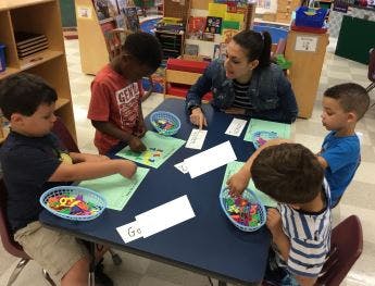 Adult and children at a table doing an activity with small objects