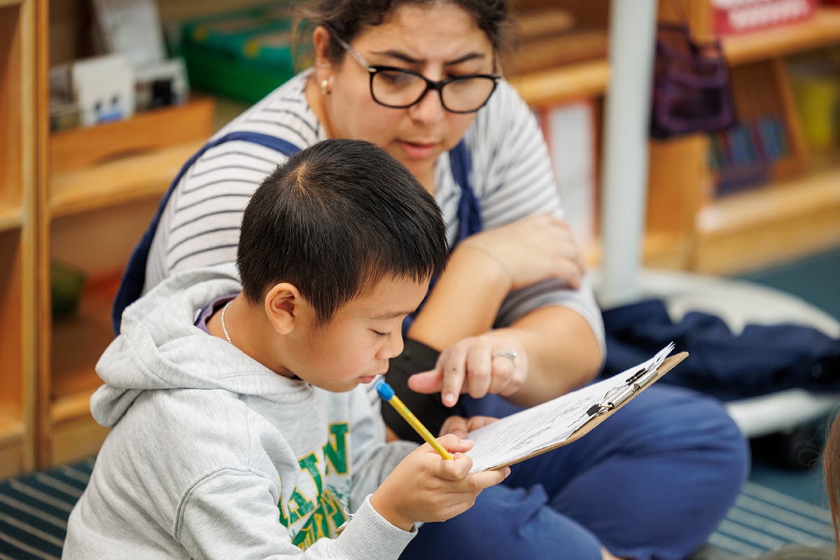 Adult and child writing on a clipboard with a pencil