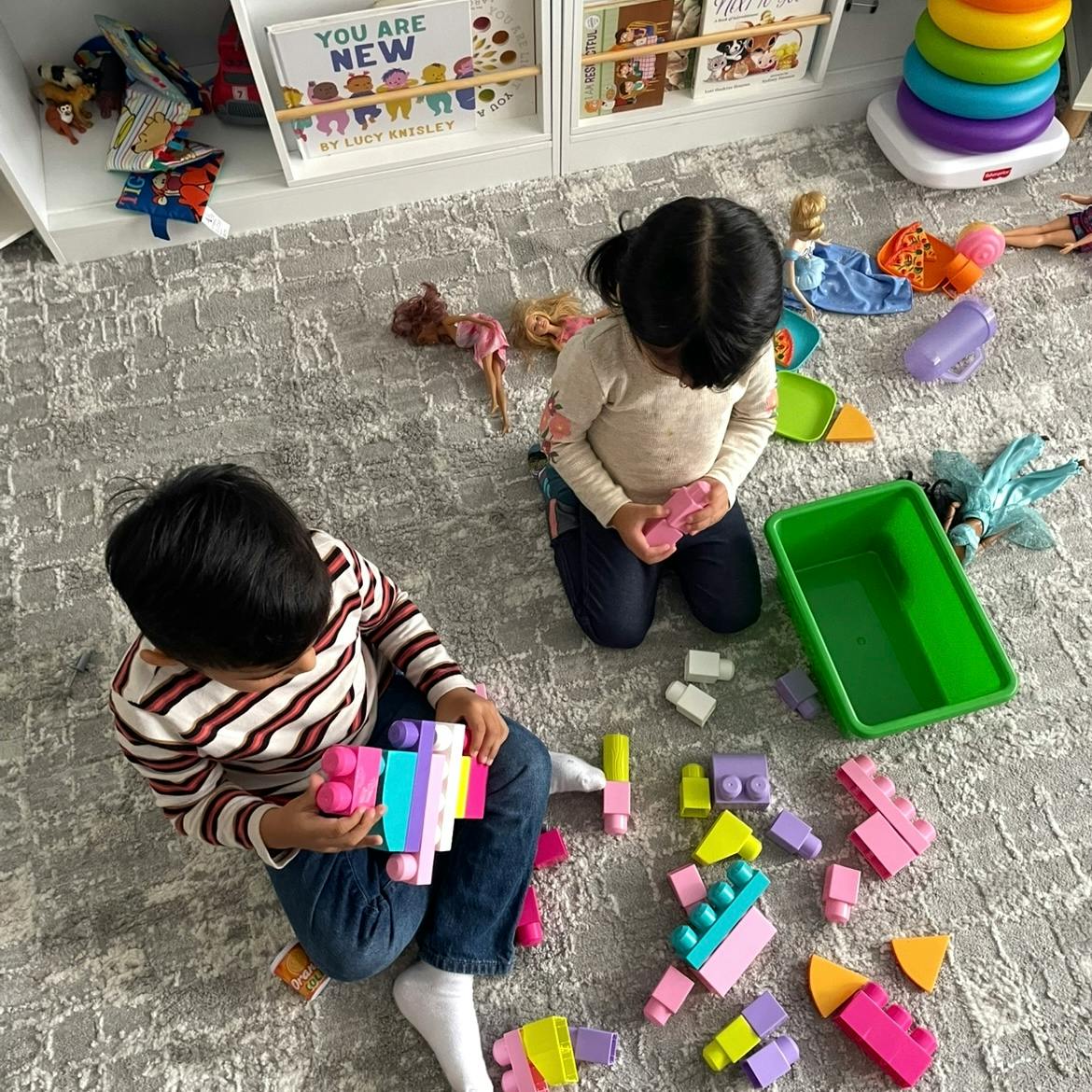 Two children playing with colorful building blocks on a rug