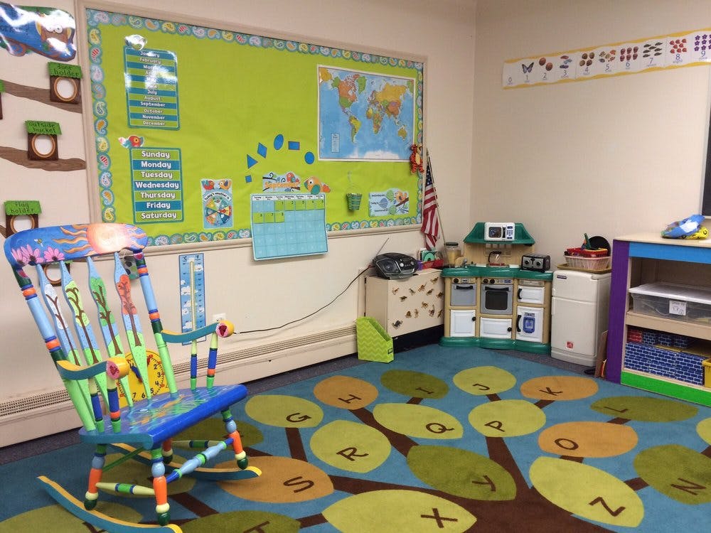 Colorful rocking chair in a classroom with a tree-patterned rug