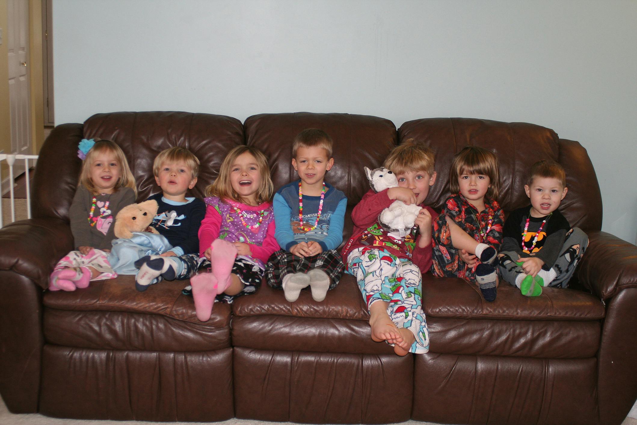 Six children sitting on a brown couch