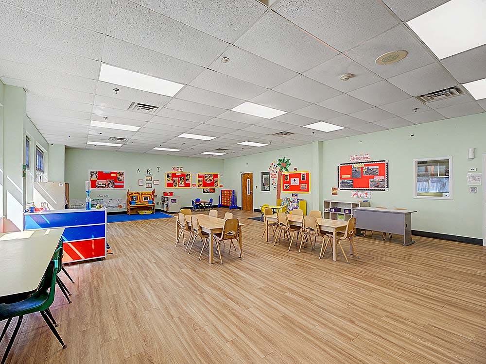 Empty classroom with small tables and chairs, and bulletin boards on the walls