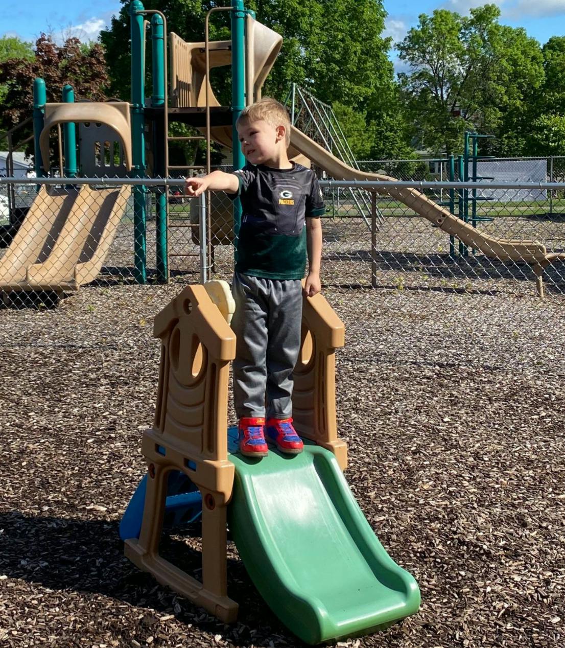 Child standing on a small slide pointing