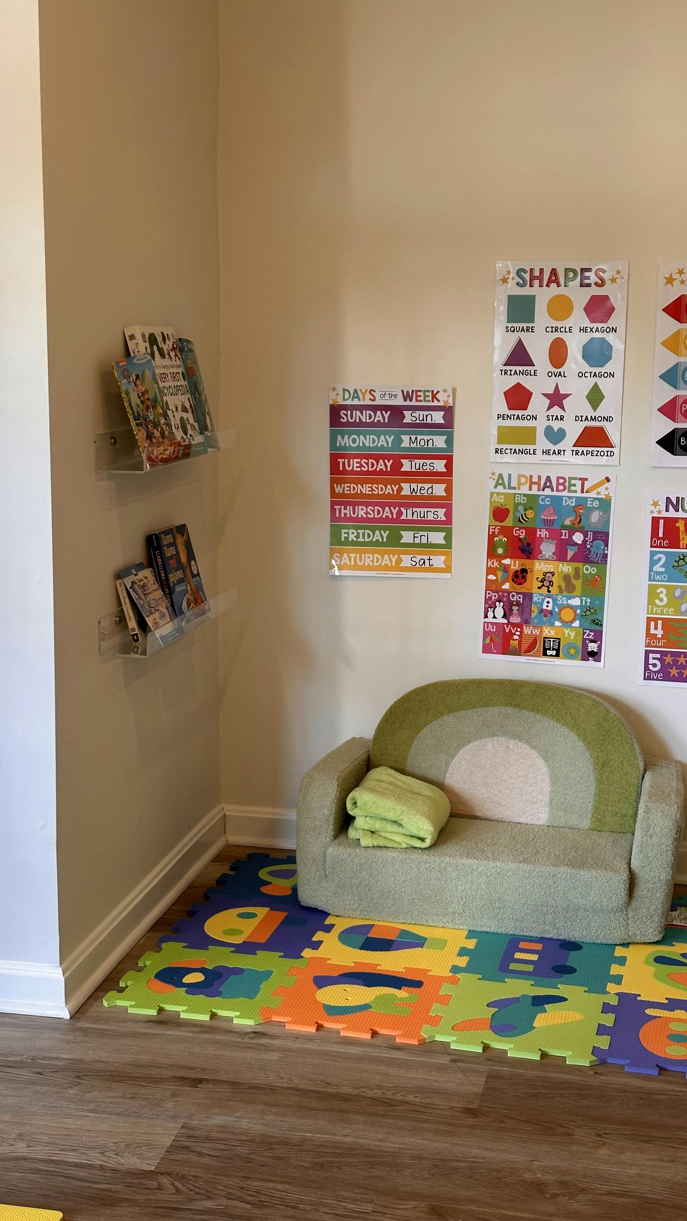Child's sofa on a colorful playmat with educational posters on the wall
