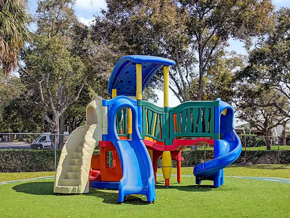 Colorful playground structure with slides and a platform on green artificial turf