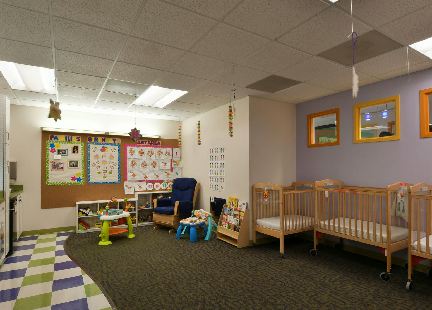 Nursery room with cribs, a rocking chair, and play items