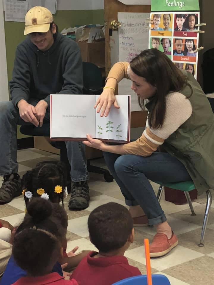 Adults reading a book to children in a classroom