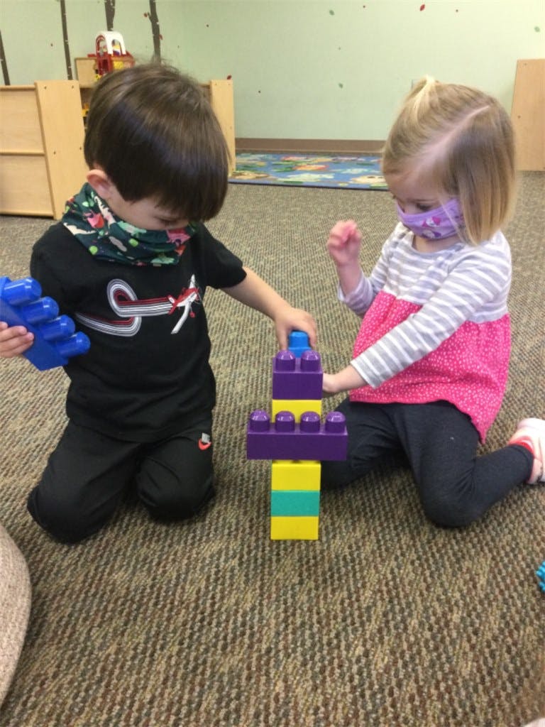 Two children playing with colorful building blocks on the floor