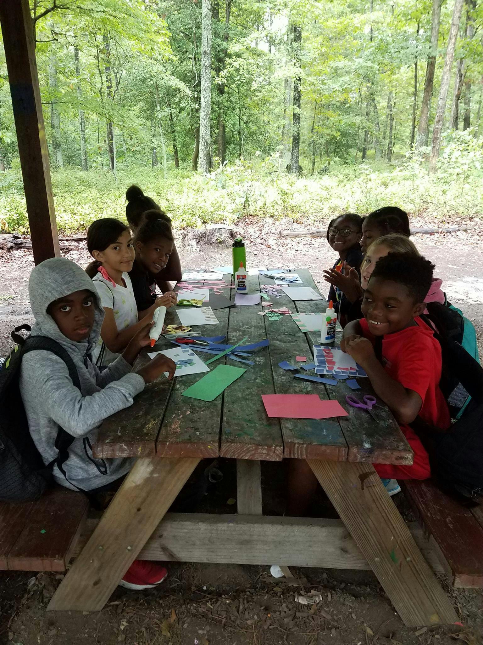 Children doing crafts at a picnic table outdoors