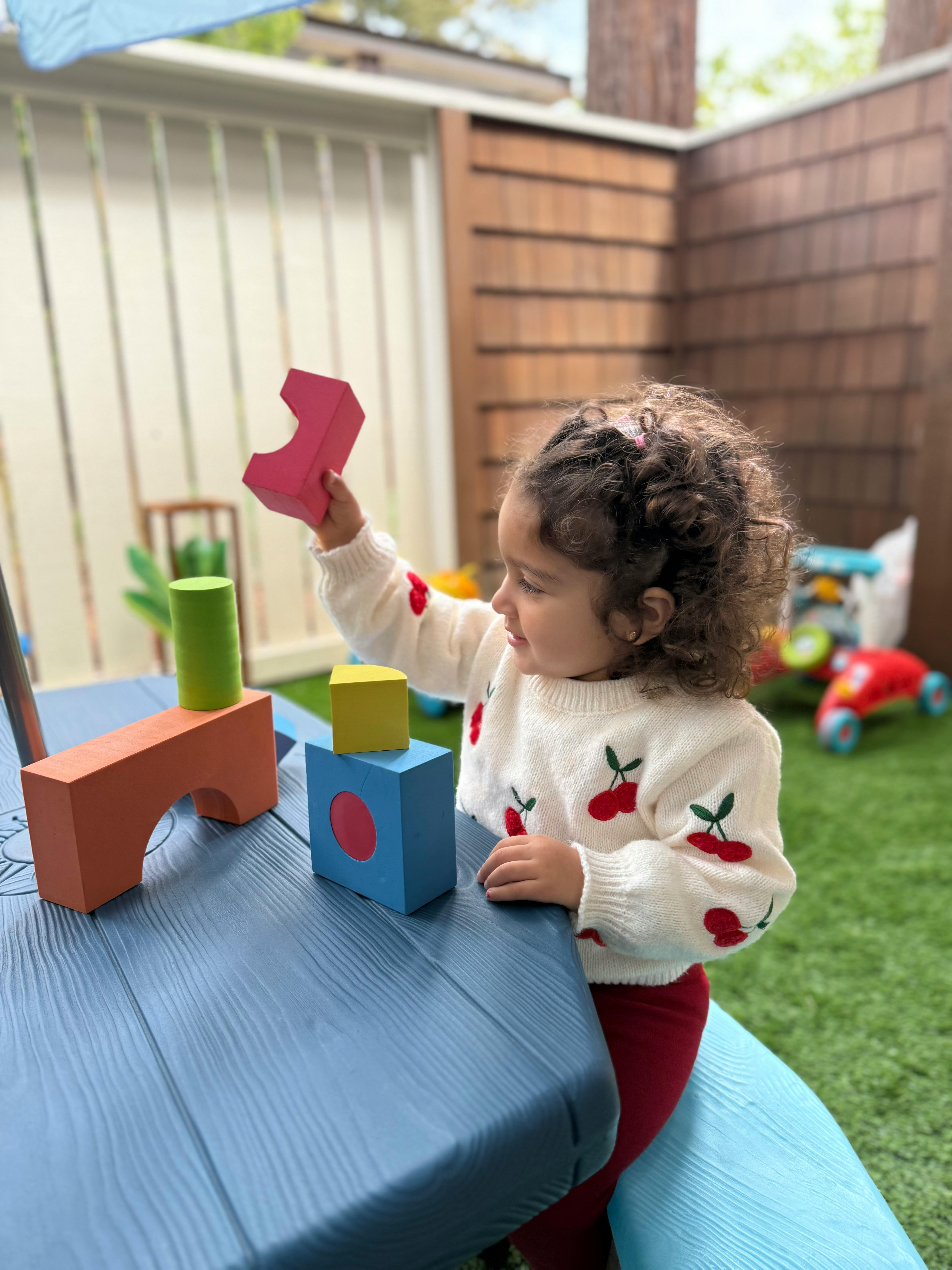 Child playing with colorful building blocks on a blue table