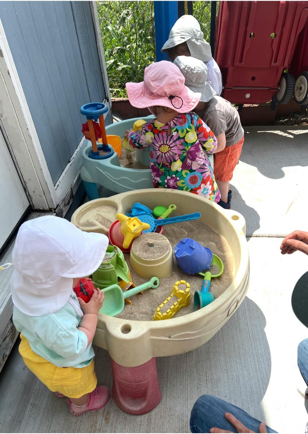 Children playing with sand and toys at a outdoor sensory table