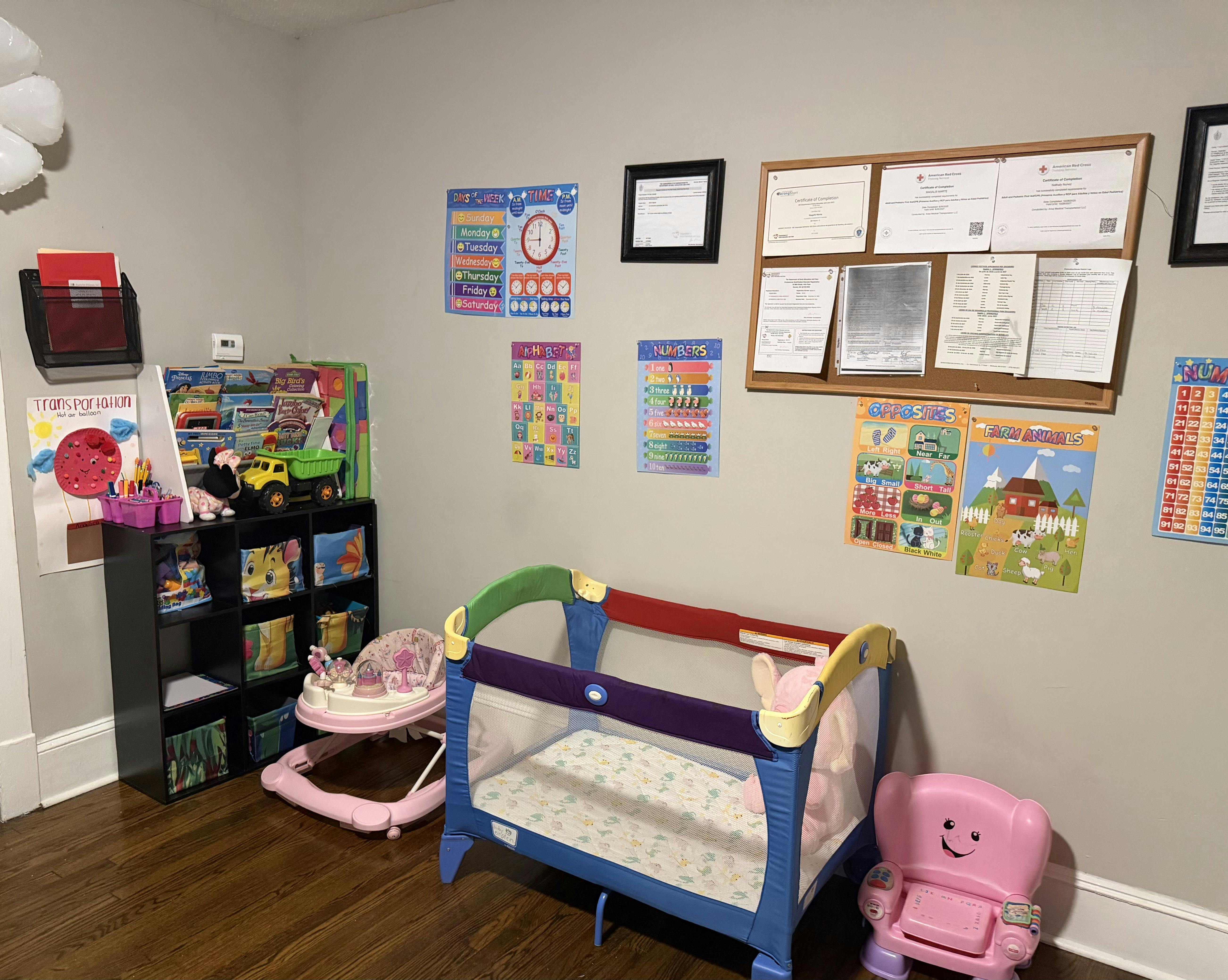 Childcare room with learning posters, a pack and play, and children furniture