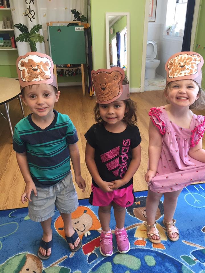 Three children wearing bear-themed paper hats