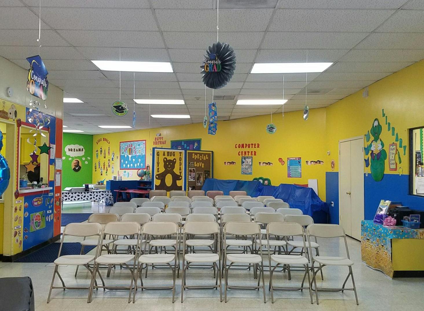 Rows of empty folding chairs in a colorful room with yellow and blue walls