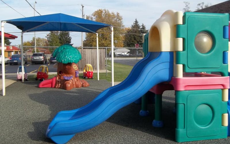 Playground with a blue slide, climbing structure, and three toy cars