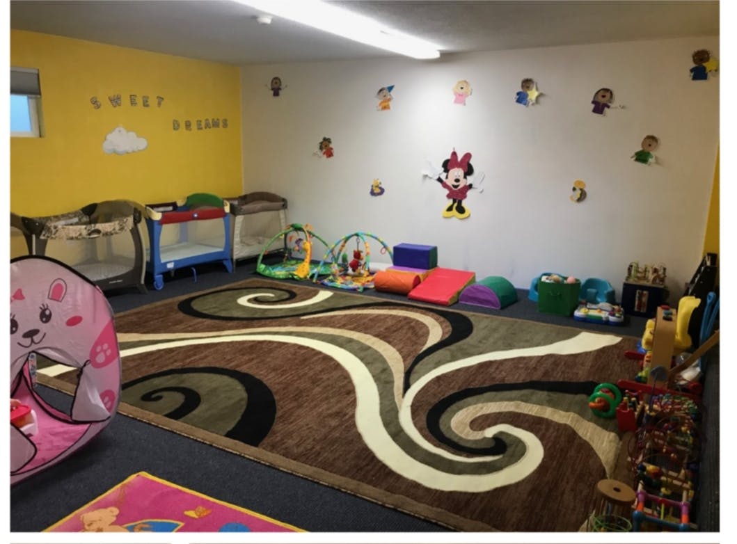 Playroom with a patterned rug, cribs, and toys